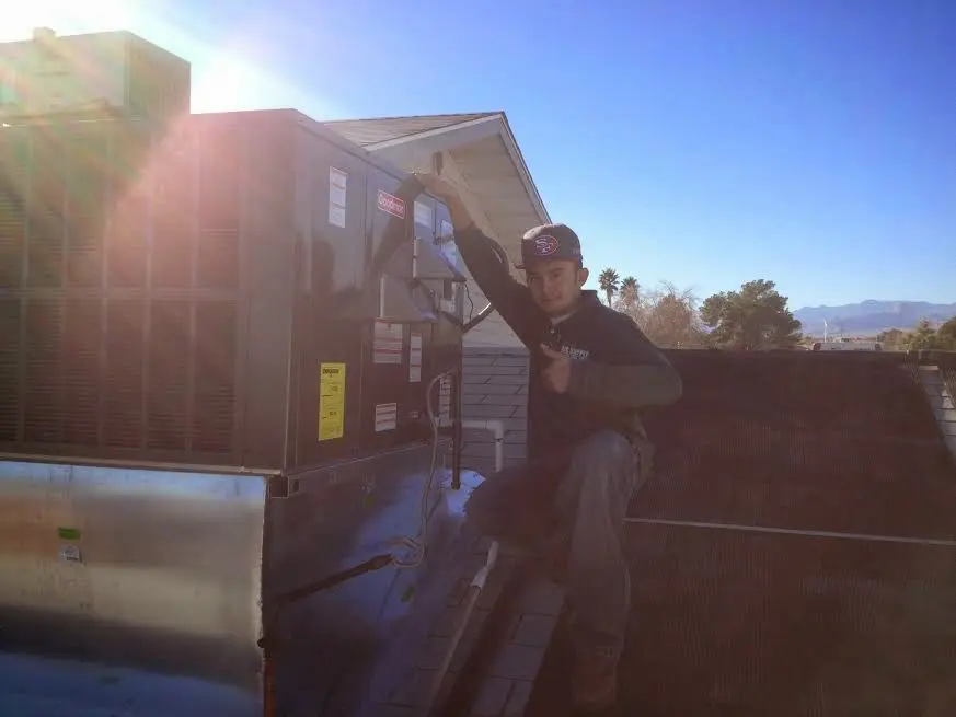 HVAC technician performing AC Tune-Up on a rooftop unit in East Rutherford